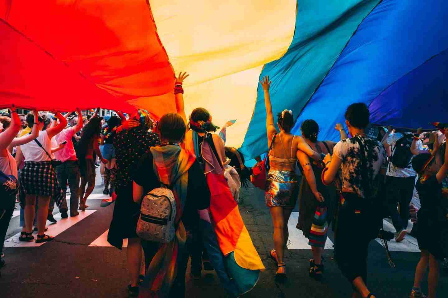 People walking under a Pride flag