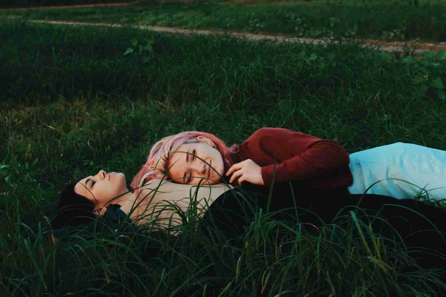 two women lying on green grass