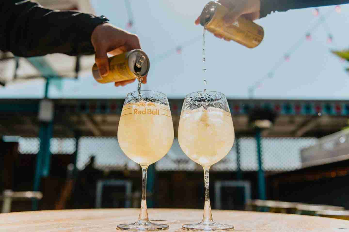 person pouring yellow liquid on clear drinking glass - Rooftop Bars in London