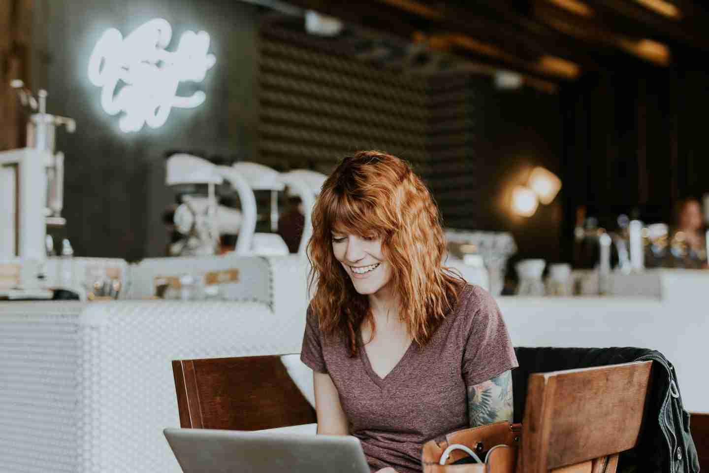 woman sitting on brown wooden chair while using silver laptop computer in room looking for Free Lesbian Dating Apps & Site