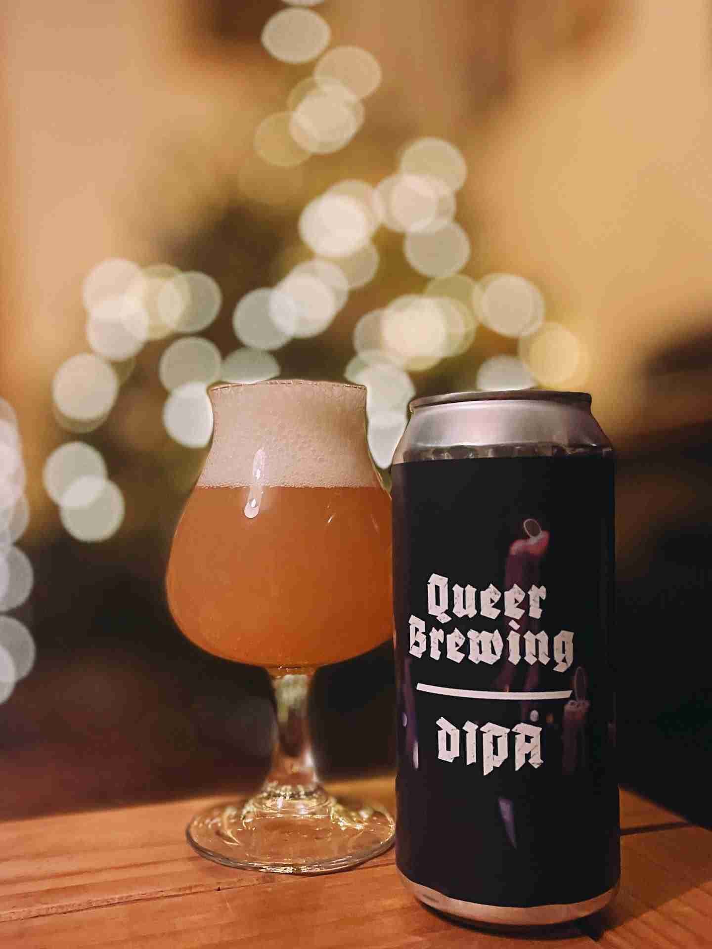 queer brewing craft beer in glass with christmas lights in background