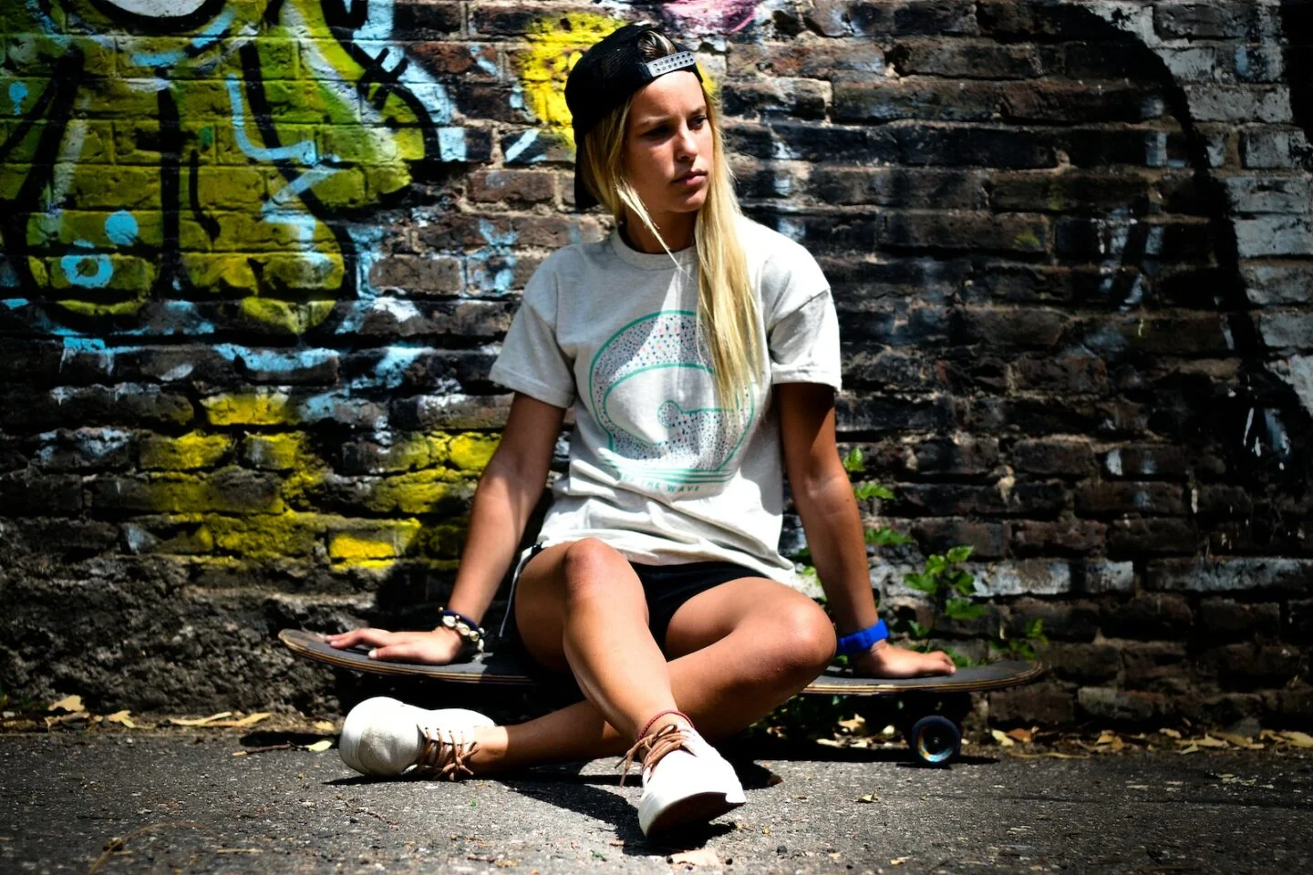 woman in white shirt sitting on skateboard