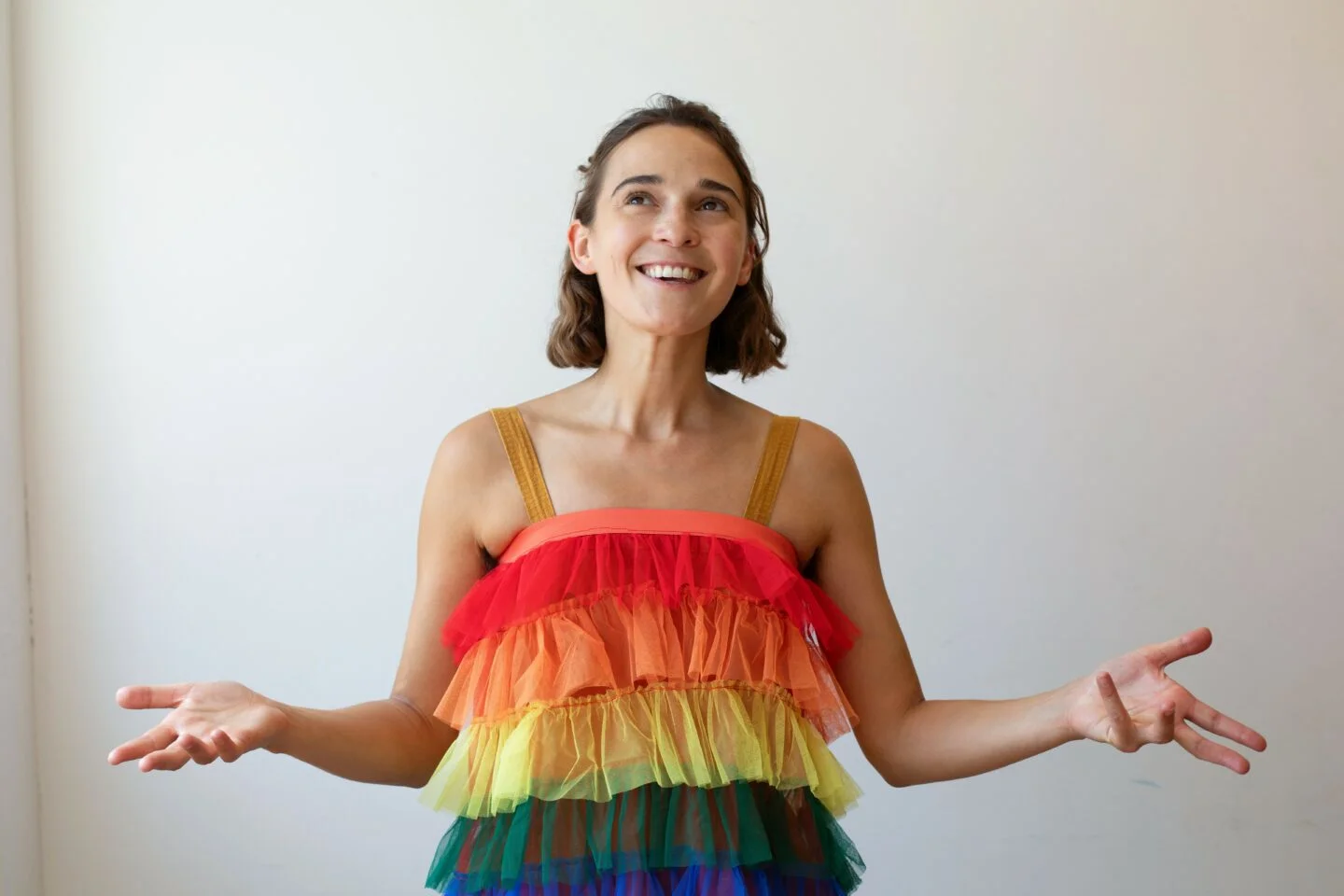 Philippa in a rainbow dress smiling on a white background