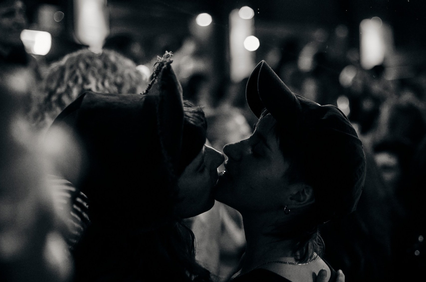 Image of two people at BP events kissing. Both are wearing a baseball cap. It's in black and white.
