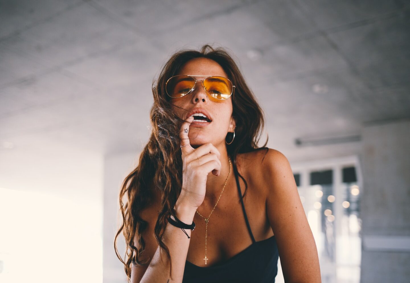 woman wearing black tank top making post with a finger tatoo