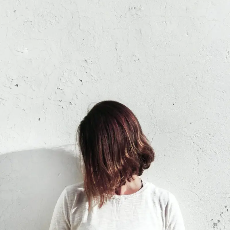 woman in white shirt leaning on wall during daytime