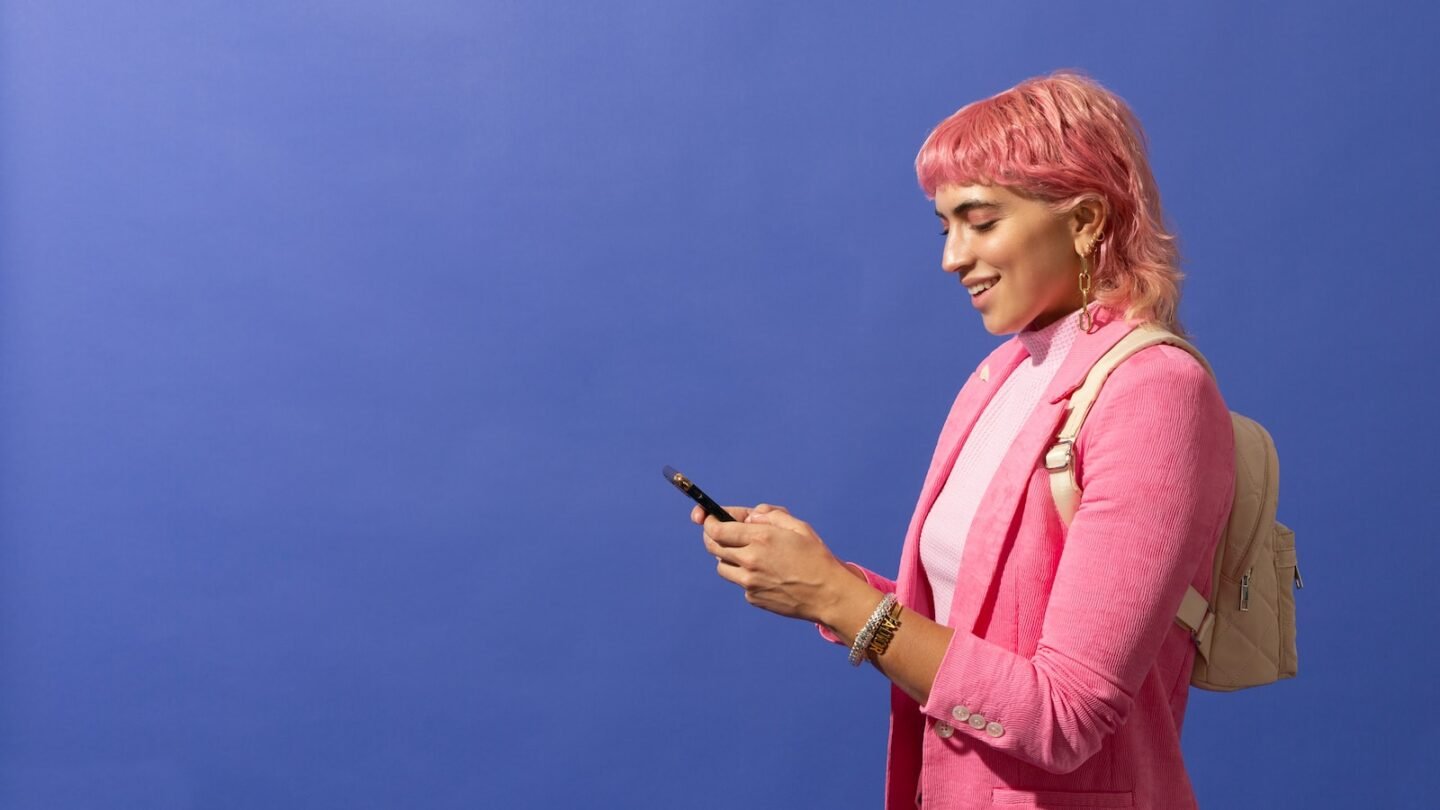 a woman with pink hair is looking at her phone